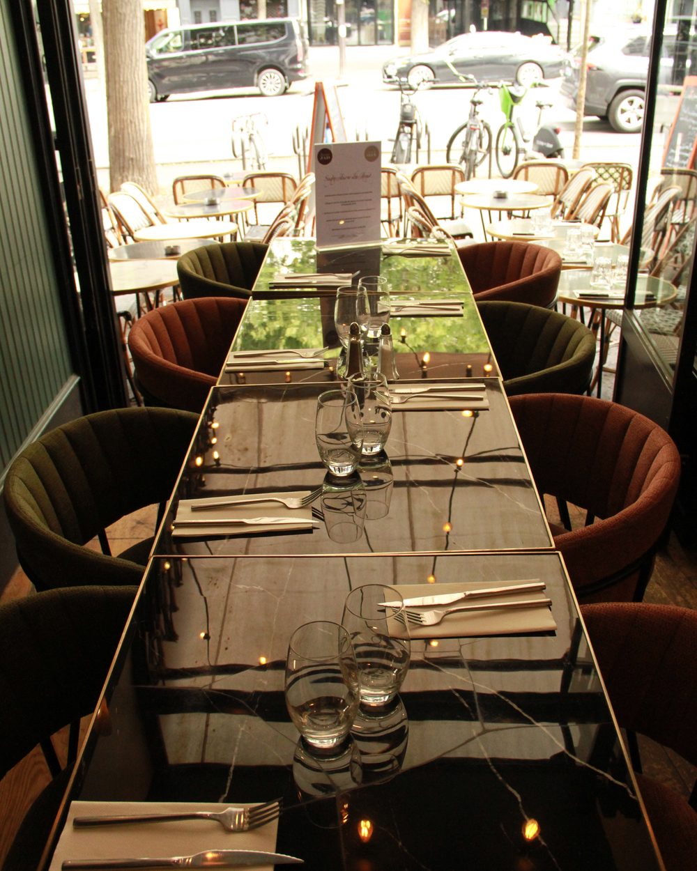 A long table laid at Bistrot Jad, glasses and cutlery lined up before service