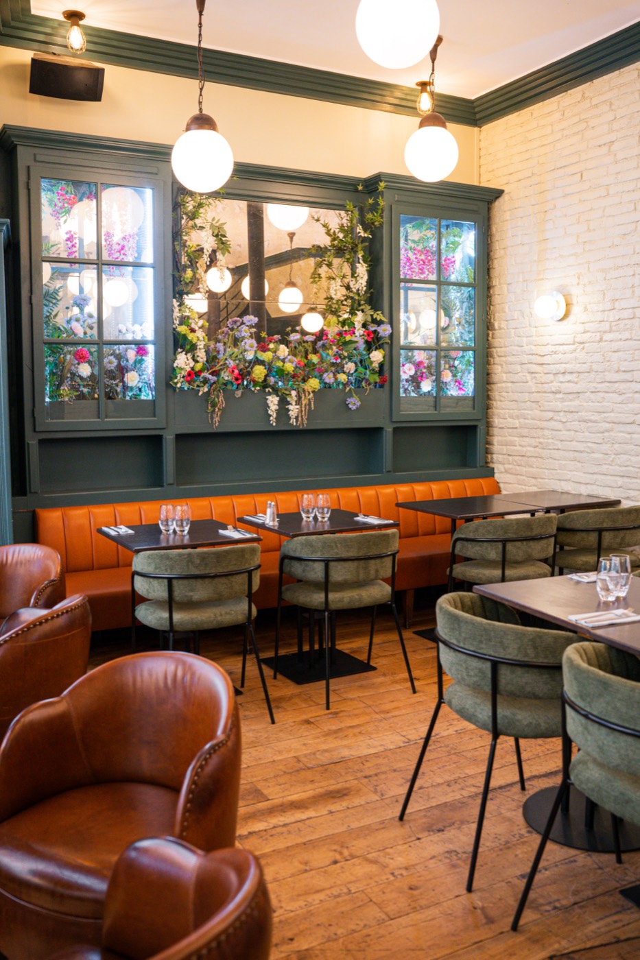Green flowered cabinets and cognac leather armchairs at Bistrot Jad